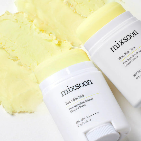 Dos barras de protector solar mixsoon Bean Sun Stick sobre una pasta amarilla