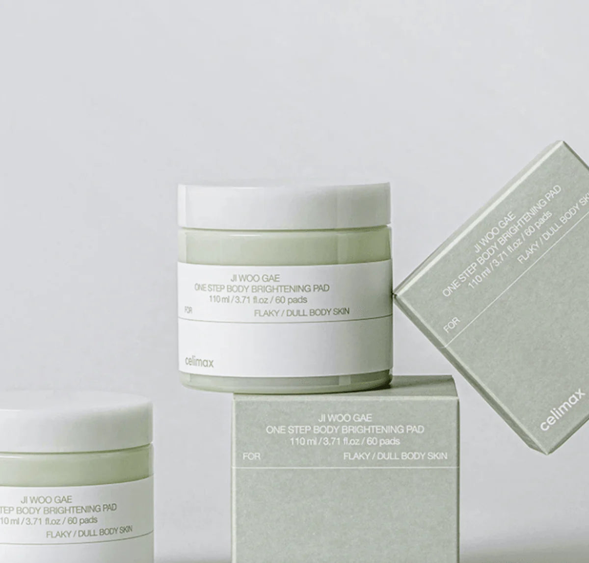 Tres frascos y cajas de discos de algodón exfoliantes Celimax Jiwoogae One Step Body Brightening Pad apilados